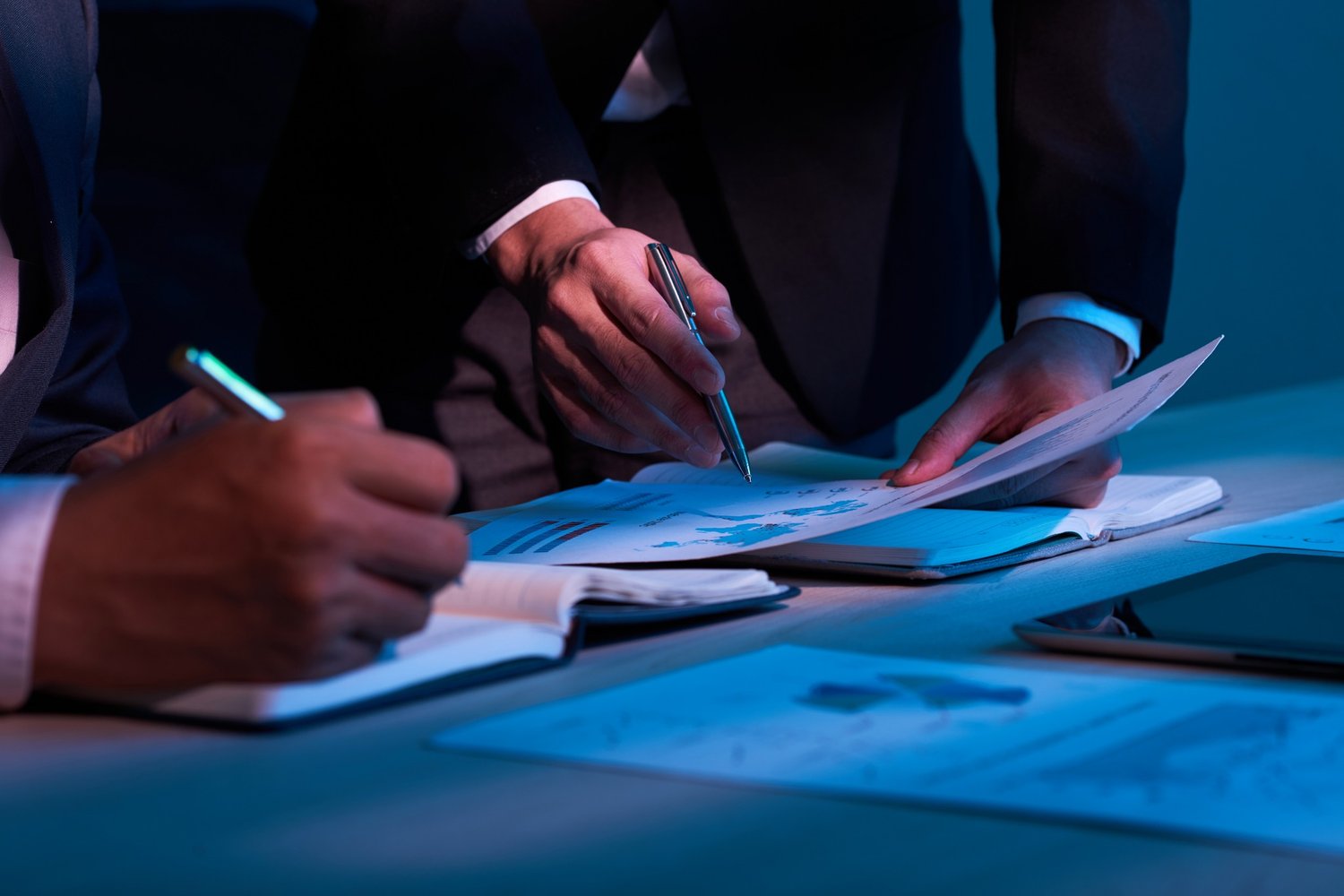 Profissionais em reunião analisando documentos e planejamento financeiro.